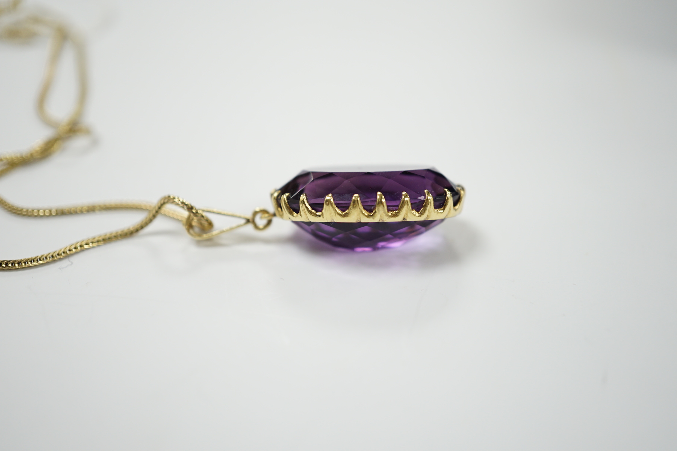 A yellow metal mounted single stone oval cut amethyst set pendant, 35mm, on a yellow metal chain, 48cm, gross weight 10.7 grams